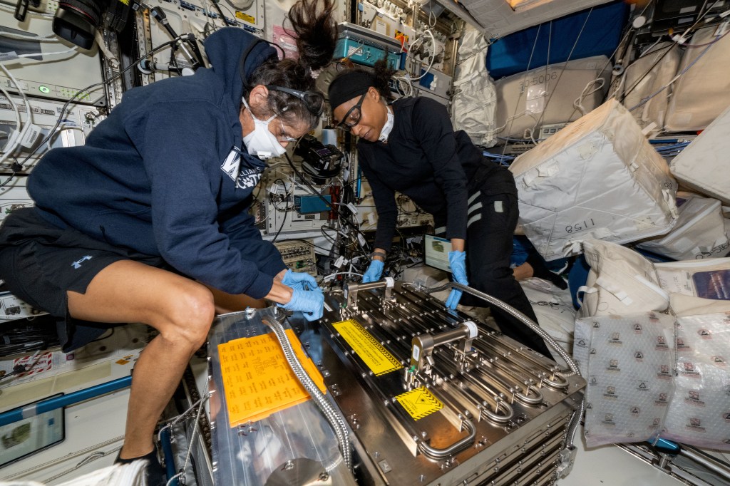NASA astronauts (from left) Suni Williams, Pilot for Boeing's Crew Flight Test, and Jeanette Epps, Expedition 71 Flight Engineer, configure the Metal 3D printer inside the Columbus laboratory module. They retrieved an experimental sample printed with stainless steel, replaced a substrate in the advanced manufacturing hardware, then reinstalled the 3D printer back in Columbus' European Drawer Rack-2. Researchers are exploring how the Metal 3D printer operates in the microgravity conditions of weightlessness and radiation as well as its ability to manufacture tools and parts on demand during space missions.