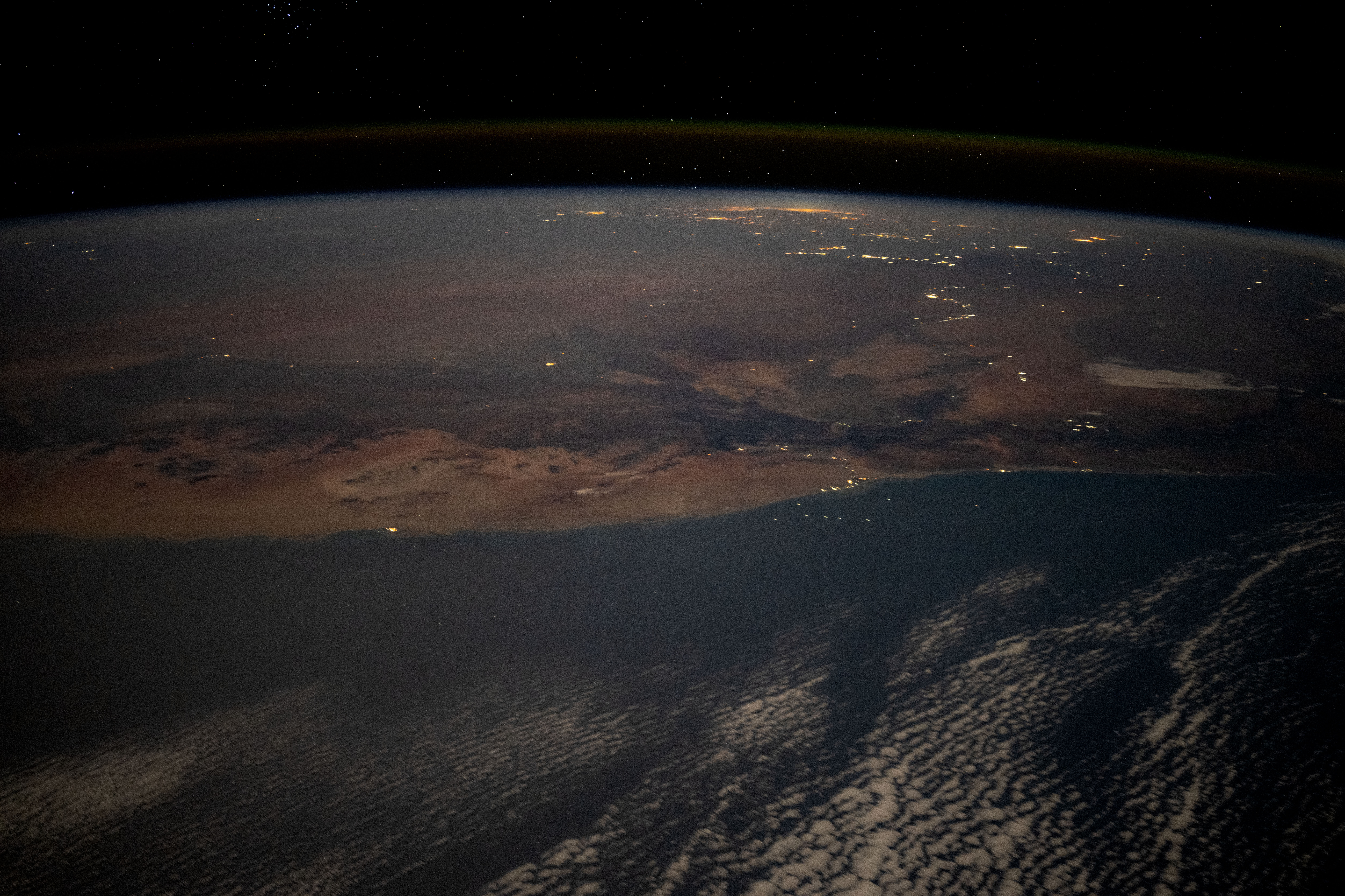 The desert coast of Namibia and the city lights of Johannesburg, South Africa, and surrounding areas on Earth's horizon are pictured from the International Space Station as it soared 263 miles above the Atlantic Ocean in this nighttime photograph.