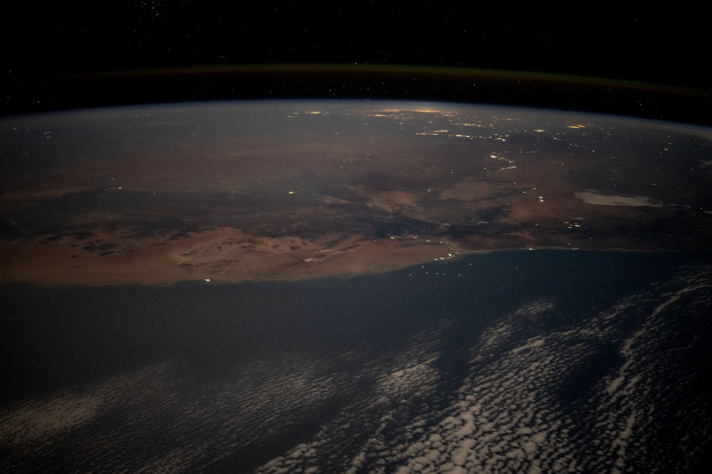 The desert coast of Namibia and the city lights of Johannesburg, South Africa, and surrounding areas on Earth's horizon are pictured from the International Space Station as it soared 263 miles above the Atlantic Ocean in this nighttime photograph.