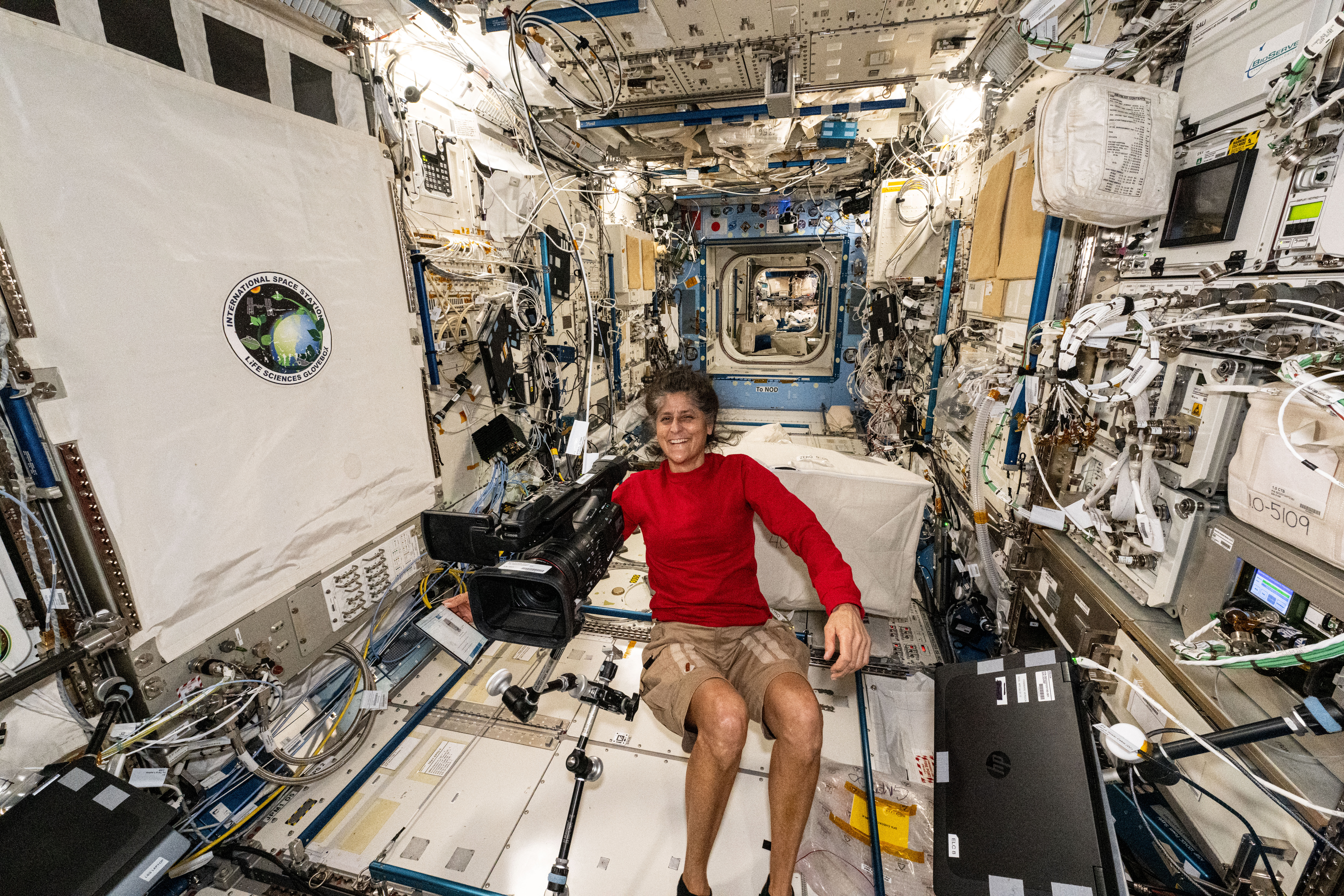 NASA astronaut and Boeing's Crew Flight Test Pilot Suni Williams smiles for a portrait in the middle of maintenance work aboard the International Space Station's Kibo laboratory module.