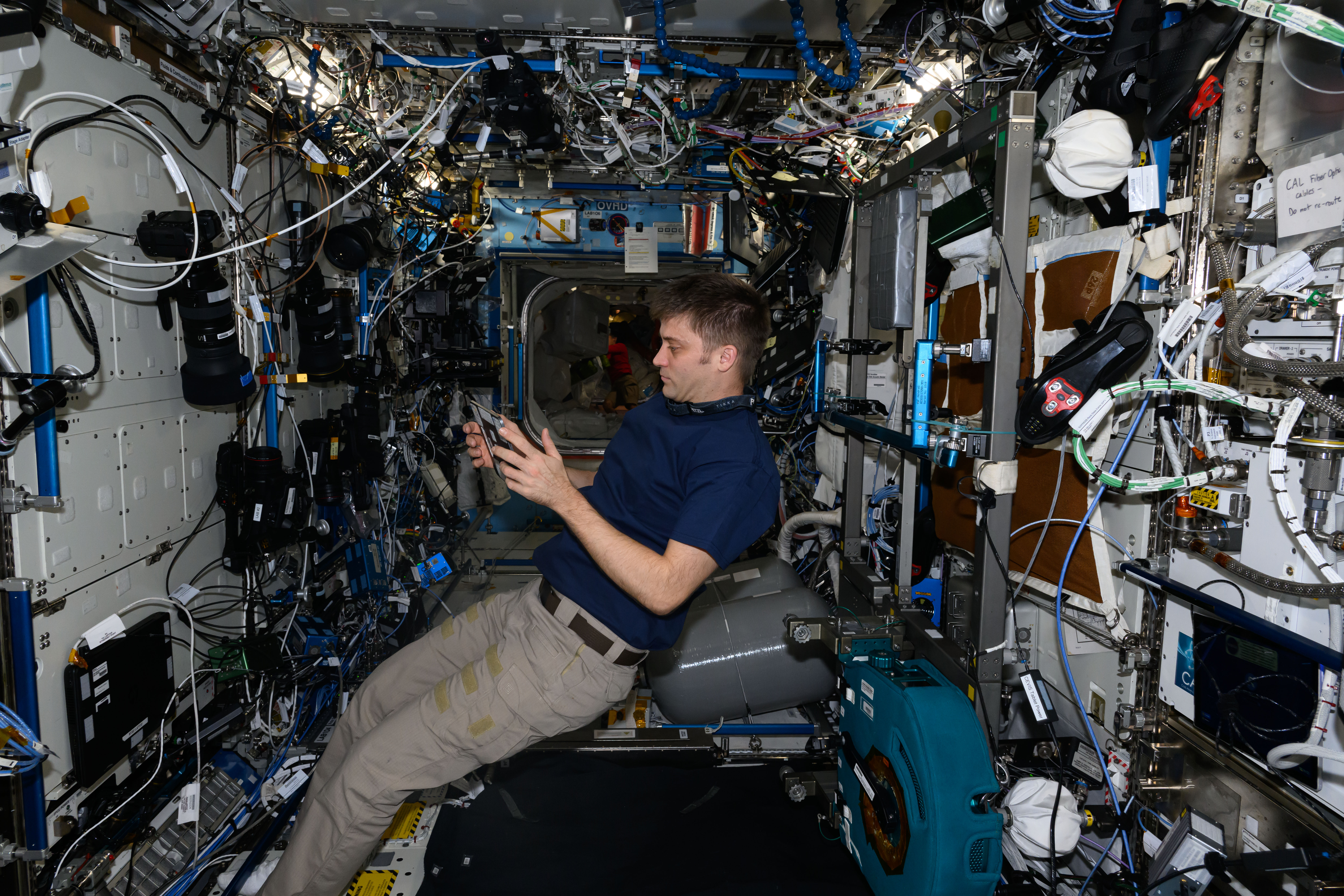 NASA astronaut and Expedition 71 Flight Engineer Matthew Dominick reviews life support maintenance procedures on a computer tablet inside the International Space Station's Destiny laboratory module.