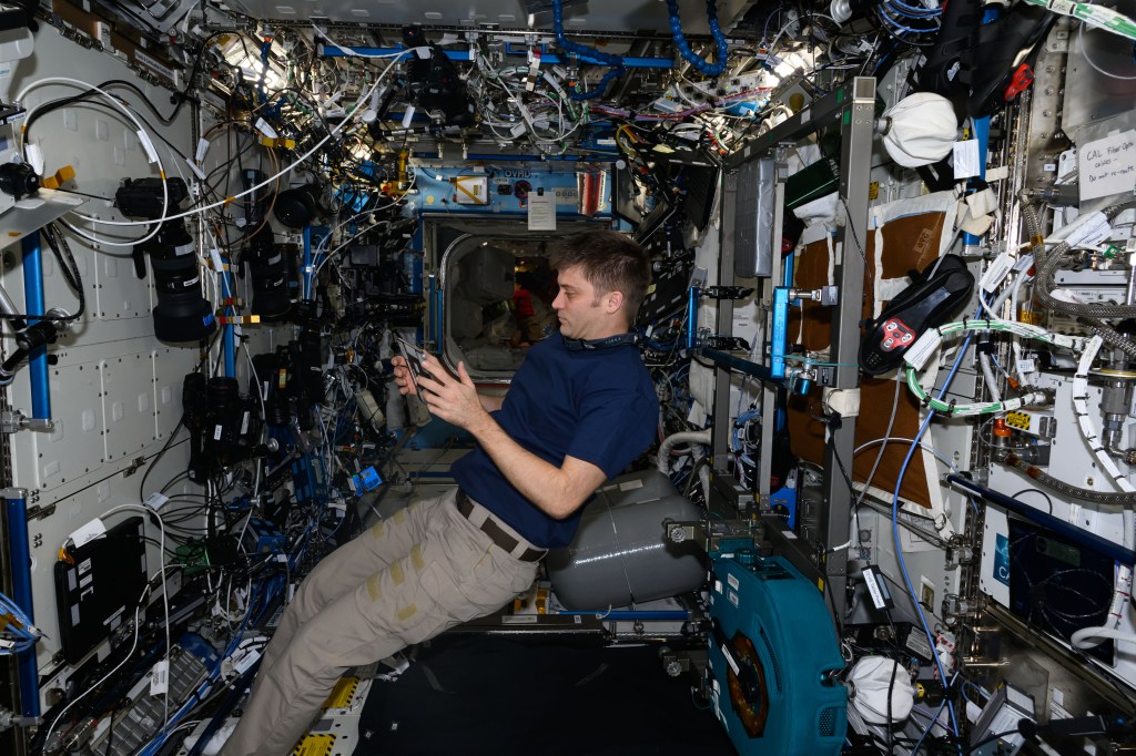 NASA astronaut and Expedition 71 Flight Engineer Matthew Dominick reviews life support maintenance procedures on a computer tablet inside the International Space Station's Destiny laboratory module.
