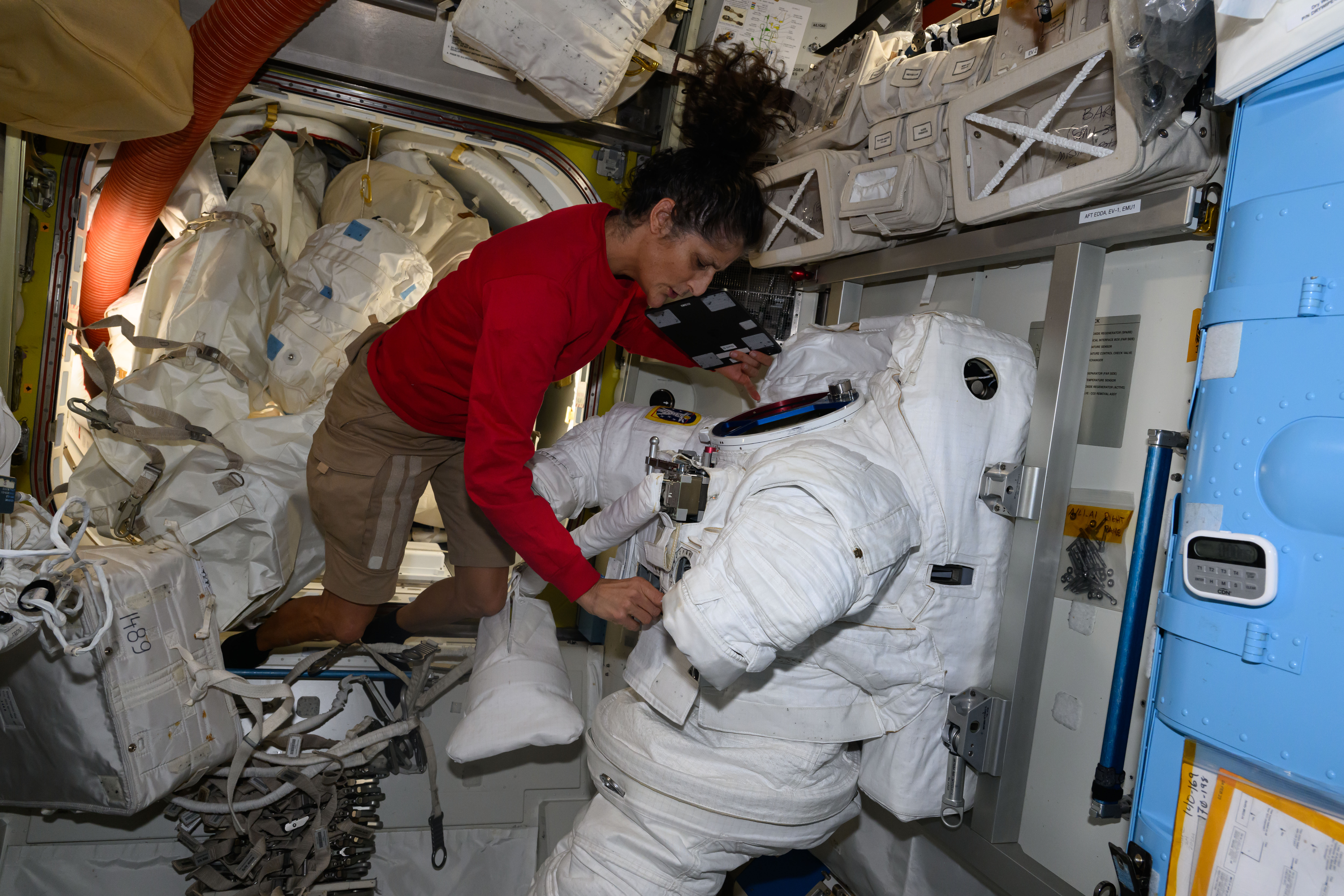 NASA astronaut Suni Williams services a spacesuit inside the International Space Station's Quest airlock.
