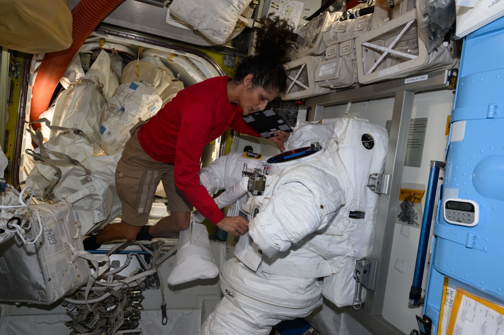 NASA astronaut Suni Williams services a spacesuit inside the International Space Station's Quest airlock.