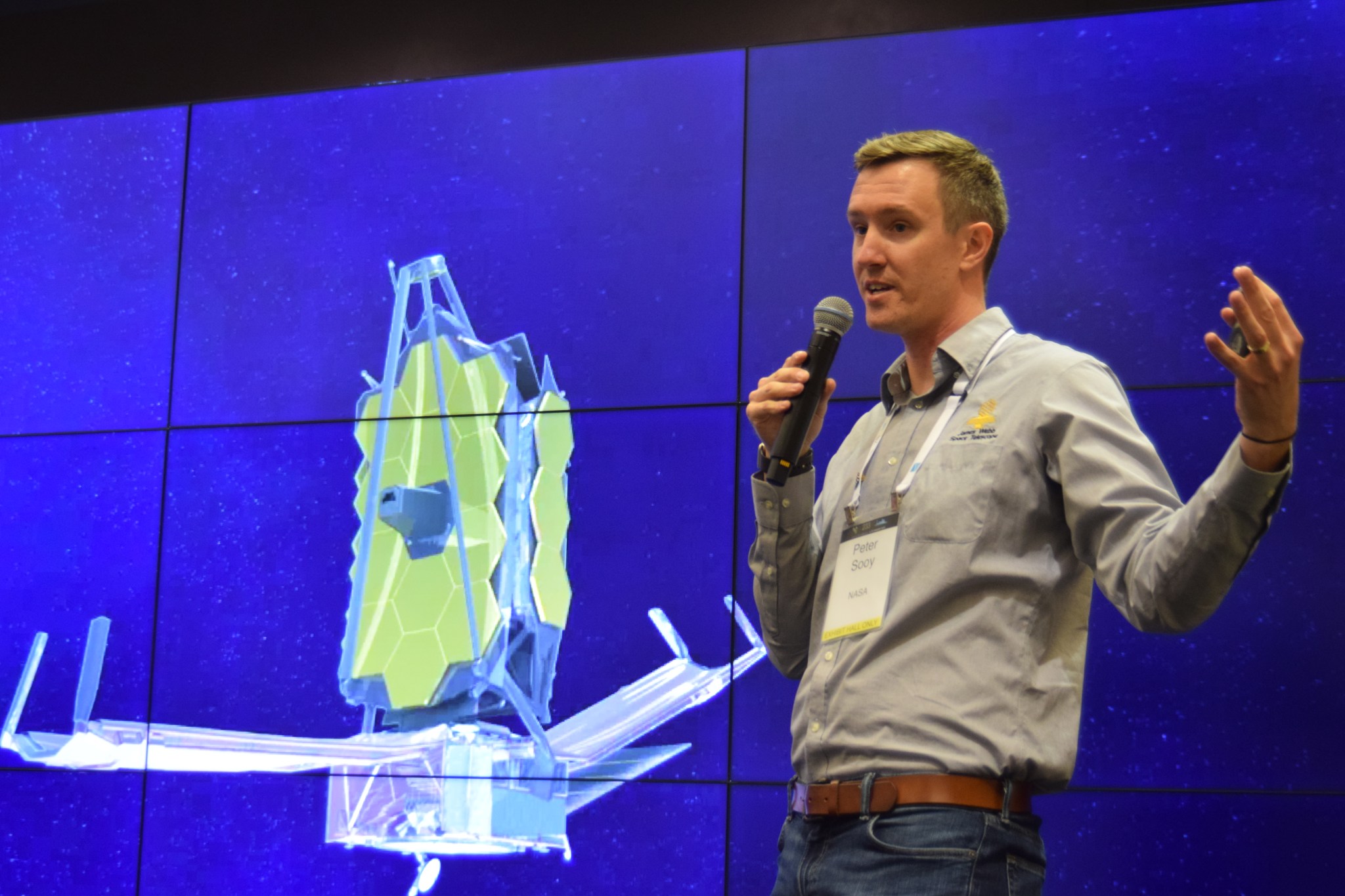 Peter speaks into a microphone in front of a large screen