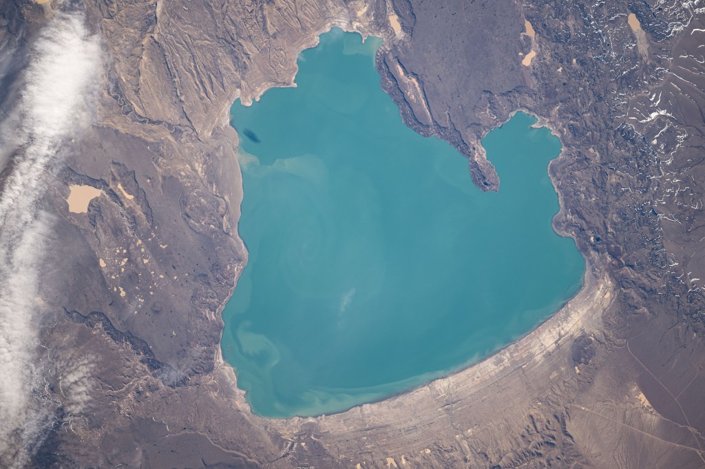 iss071e582300 (Sept. 2, 2024) -- Lake Cardiel is pictured from the International Space Station as it orbited 268 miles above Argentina. The lake is highly favored by fisherman as its alkaline water creates a rich habitat for salmon and other species to live. Its color results from nearby glaciers grinding rock into "glacial flour." The sediment is picked up by meltwater streams that feed into the lake and are slow to sink to the bottom, making the water appear a bright turquoise.