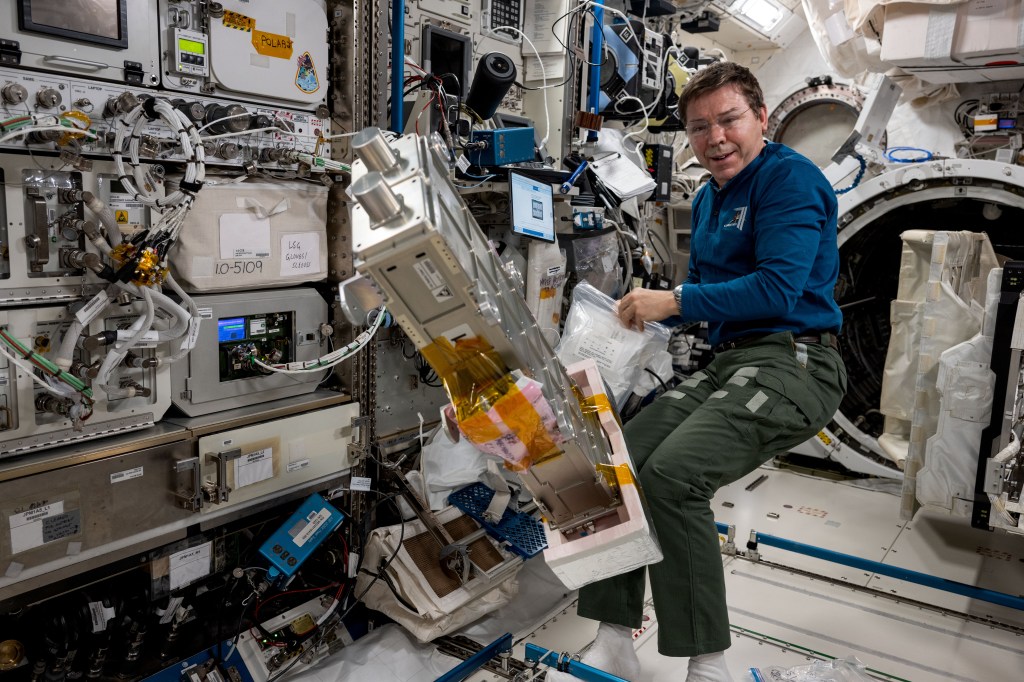 NASA astronaut and Expedition 71 Flight Engineer Mike Barratt services the small satellite orbital deployer after removing it from the Kibo laboratory module's airlock aboard the International Space Station. Earlier, the deployer released a series of CubeSats into Earth orbit for a variety of educational and research activities.
