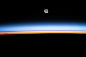 The New Moon begins setting above Earth's bright, colorful atmosphere in this long-duration photograph taken by NASA astronaut Matthew Dominick with a camera programmed for high sensitivity aboard the International Space Station.