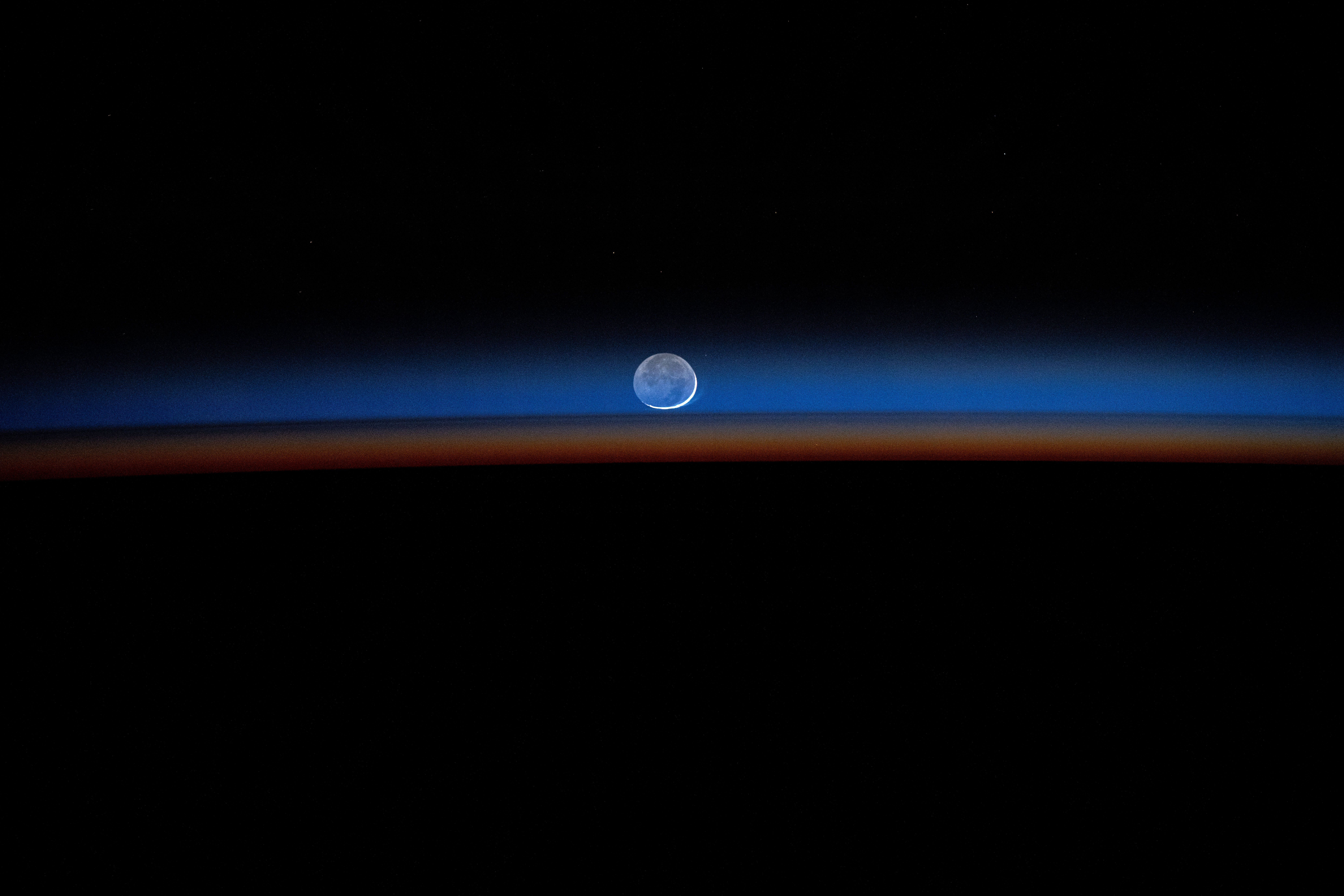 The New Moon sets behind Earth's colorful, but dimming atmosphere in this long-duration photograph taken by NASA astronaut Matthew Dominick with a camera programmed for high sensitivity aboard the International Space Station.