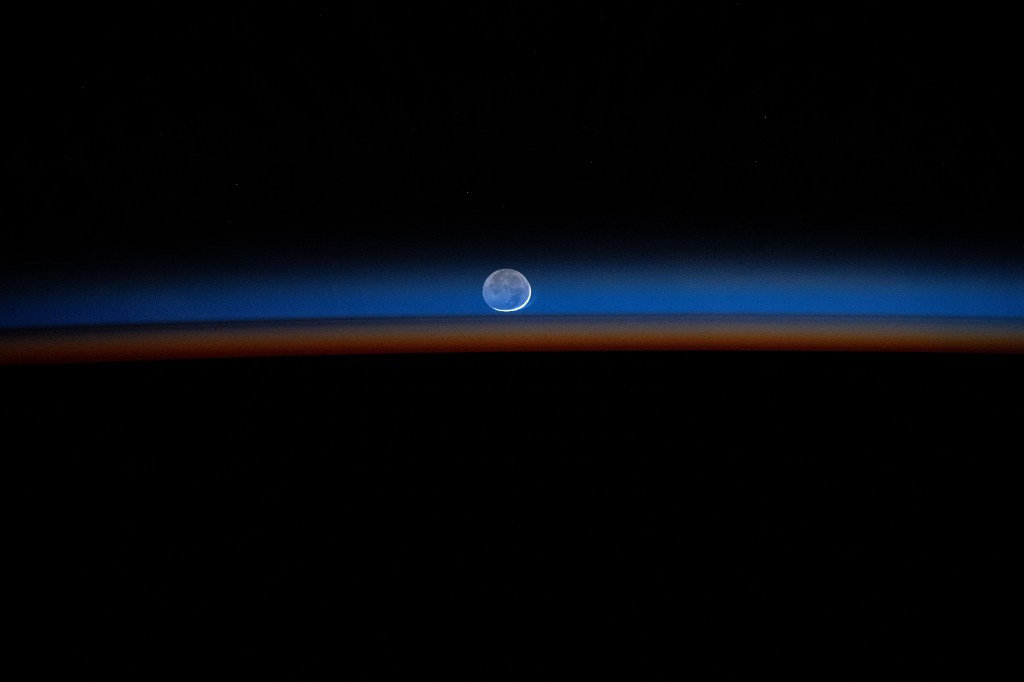 The New Moon sets behind Earth's colorful, but dimming atmosphere in this long-duration photograph taken by NASA astronaut Matthew Dominick with a camera programmed for high sensitivity aboard the International Space Station.