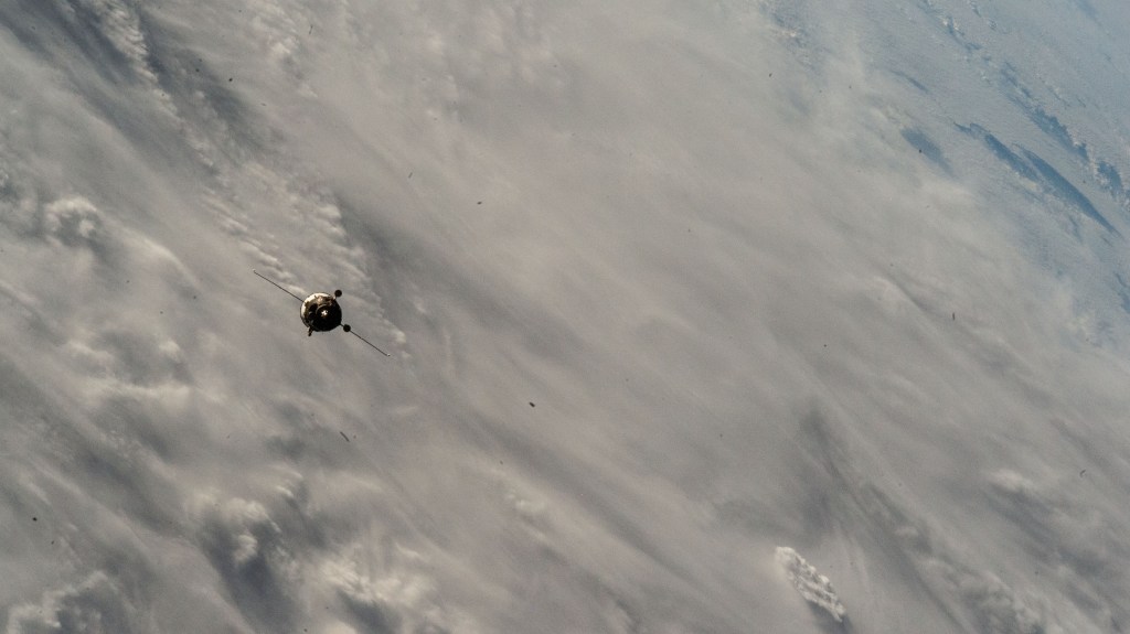 The Soyuz MS-26 spacecraft carrying NASA astronaut Don Pettit and Roscosmos cosmonauts Alexey Ovchinin and Ivan Vagner approaches the International Space Station 258 miles above a cloudy Atlantic Ocean.