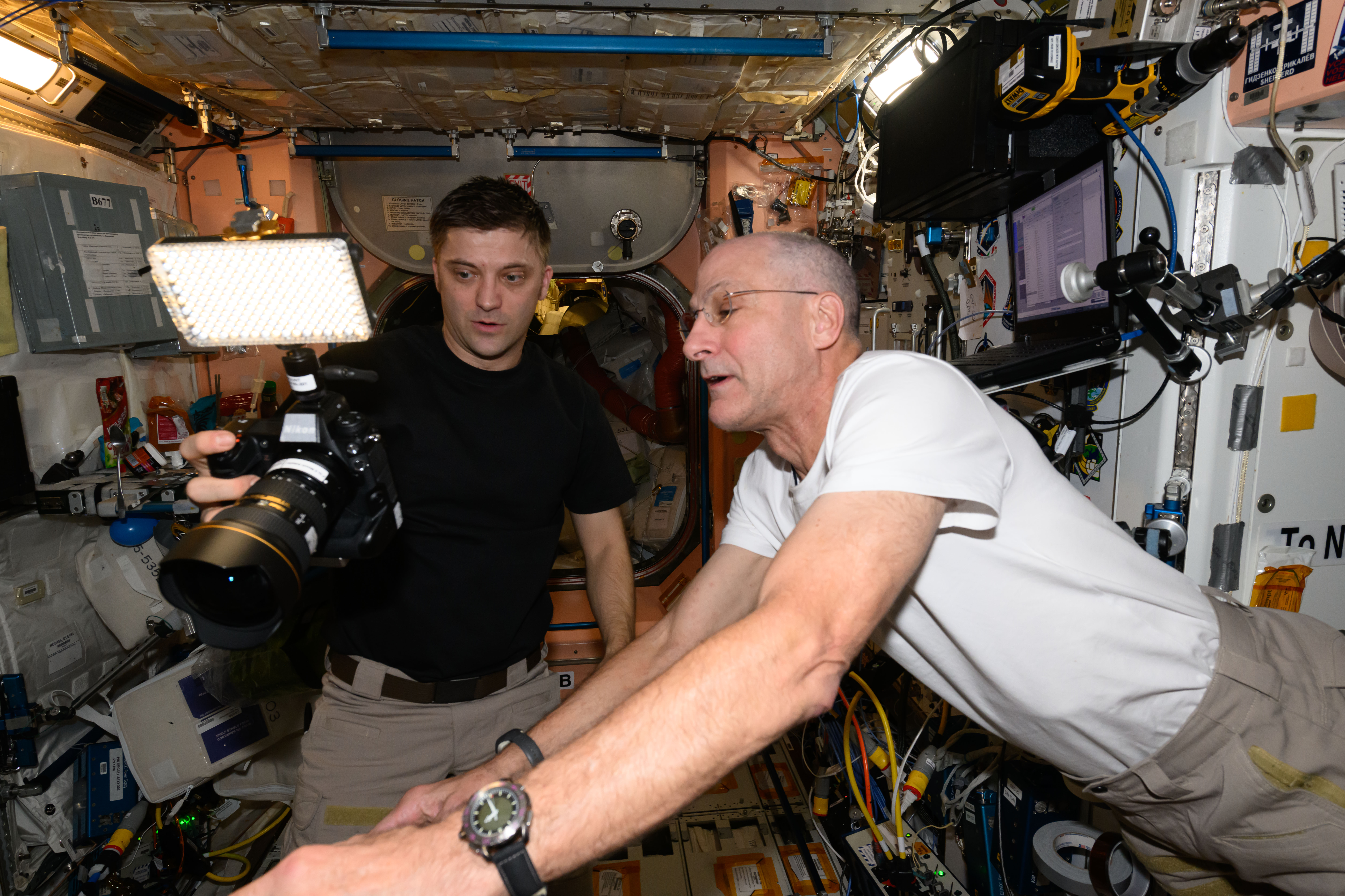 Expedition 71 Flight Engineers (from left) Matthew Dominick and Don Pettit, both from NASA, check out a digital camera aboard the International Space Station's Unity module.