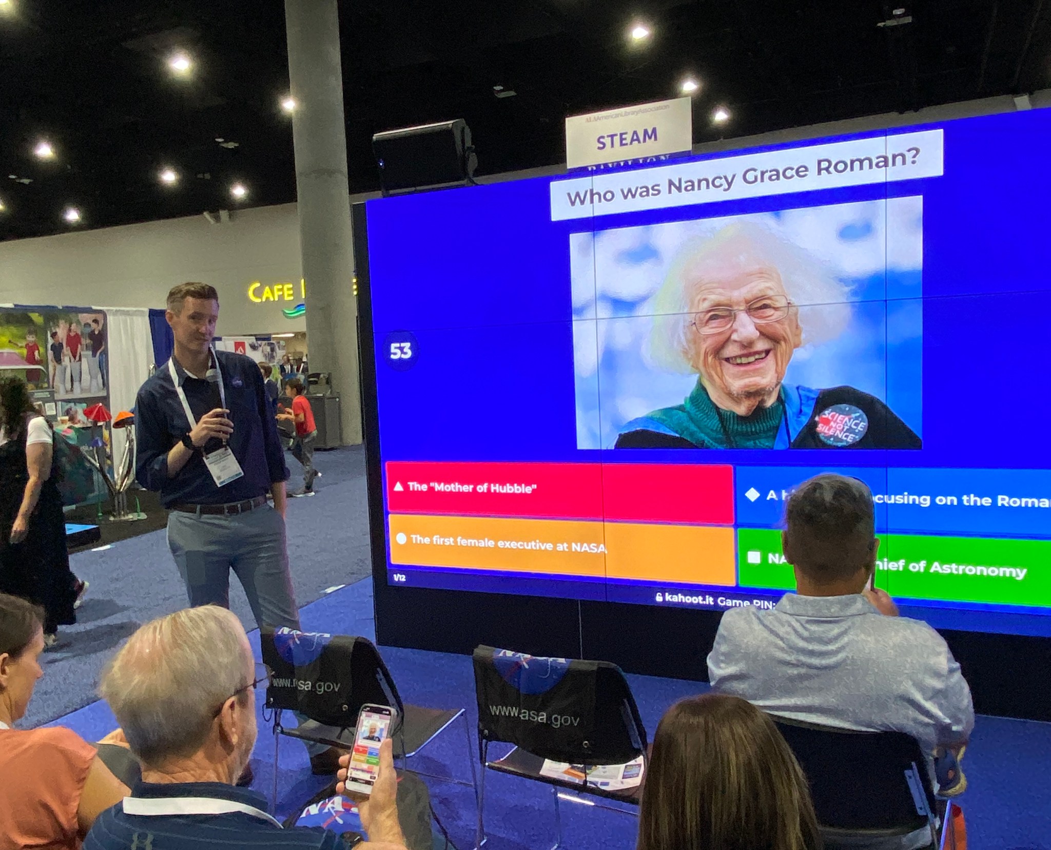 Peter stands by a large screen in front of an audience