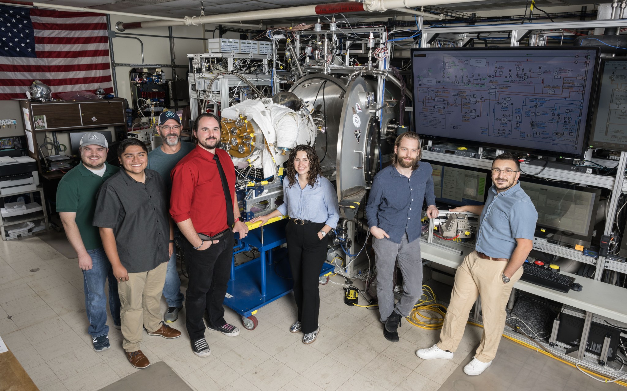 Seven members of Johnson Space Center's Chamber C testing team are pictured in a test room.