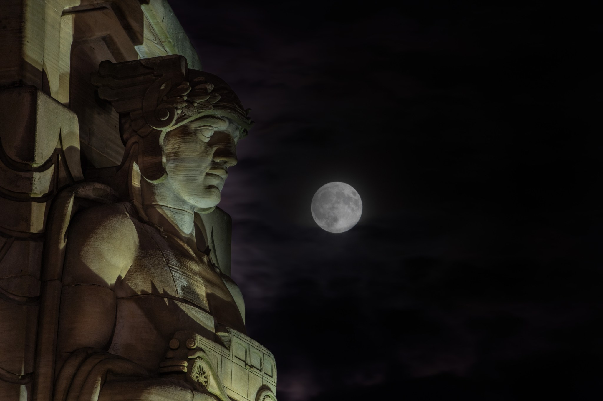 A composite image of the Moon above a Guardians of Traffic statue near downtown Cleveland. The Moon is full, a supermoon, and experienced a partial lunar eclipse (when the Earth's shadow falls upon the Moon's surface).