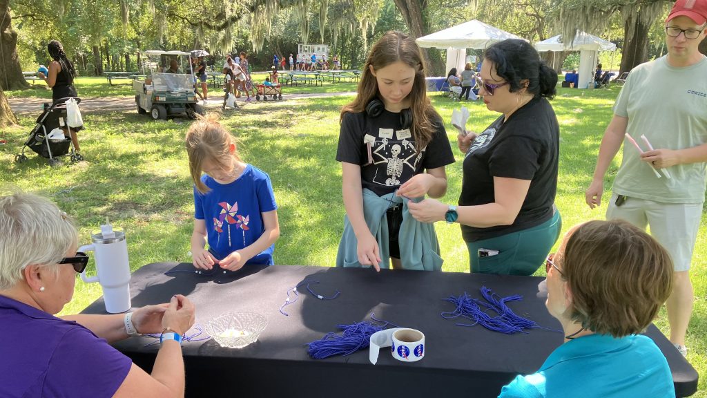 Young event-goers participate in a bracelet-making activity while attending NASA Day at the Audubon Zoo in New Orleans.