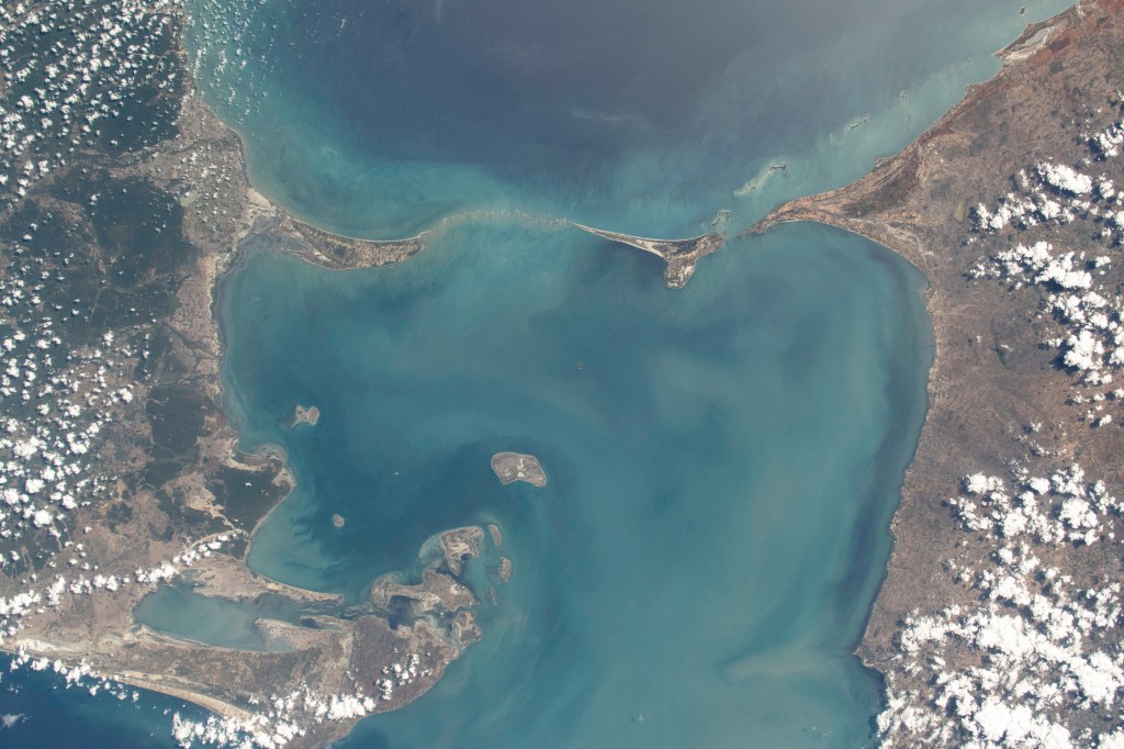 iss071e700080 (Sept. 21, 2024) -- A 48 kilometer ( 30 miles) chain of limestone shoals, formerly a bridge between India and Sri Lanka, are pictured from the International Space Station as it orbited 256 miles above. Most often called "Adam's Bridge," it separates the Palk Strait (bottom of image) from the Gulf of Mannar (top). To the right of this image is mainland India, to the left is Sri Lanka.