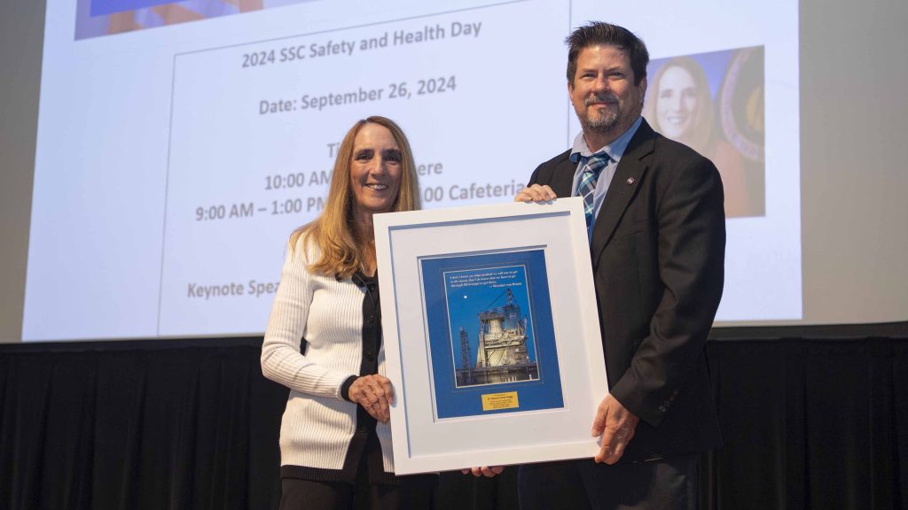 NASA Stennis Safety and Mission Assurance Director Gary Benton, right, presents framed photo to keynote speaker and former NASA astronaut Dr. Nancy Currie-Gregg