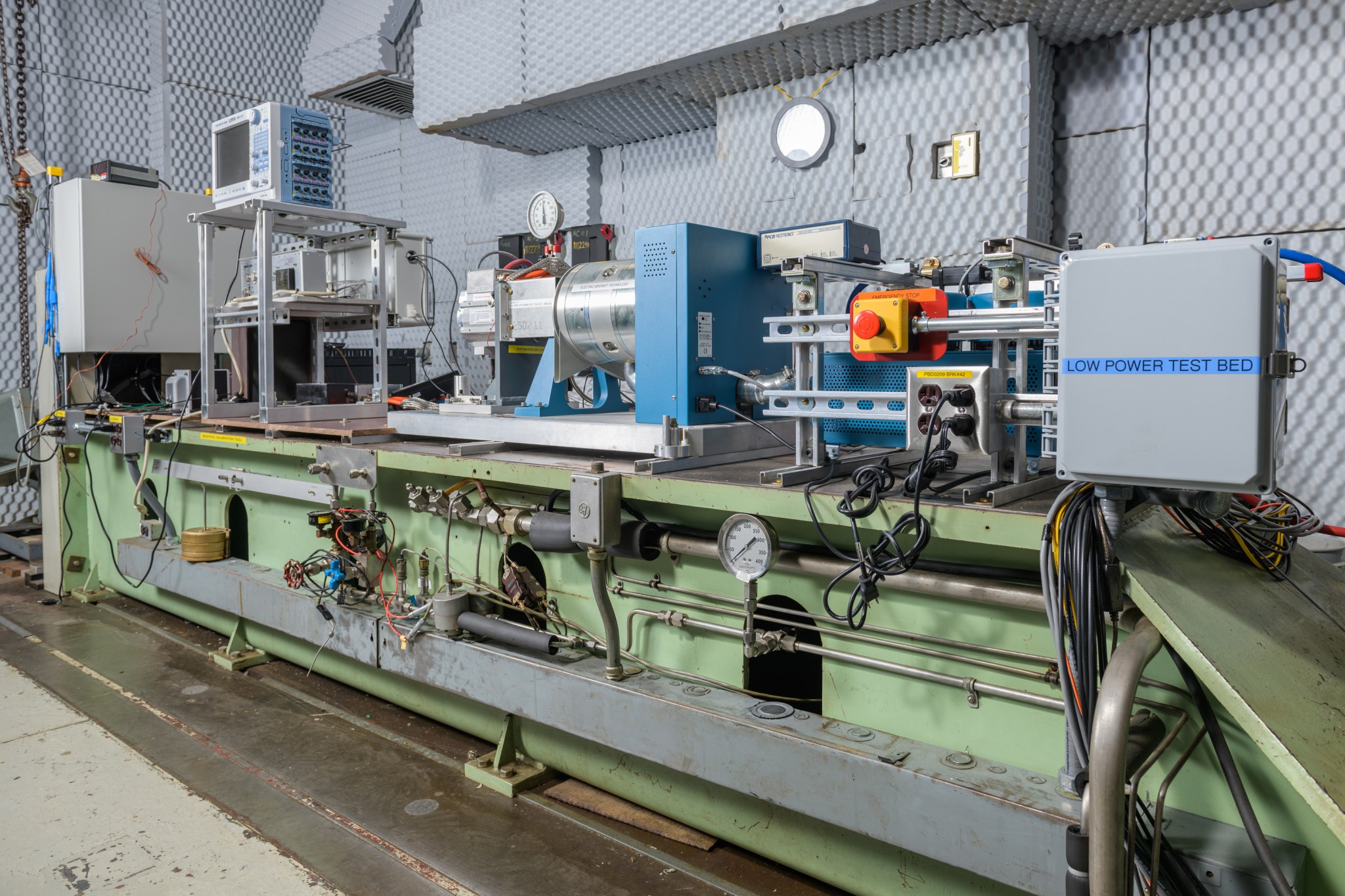 An angled view of a large, long testbed setup featuring metal hardware, wires, cables, and testing machinery for advanced air mobility research.