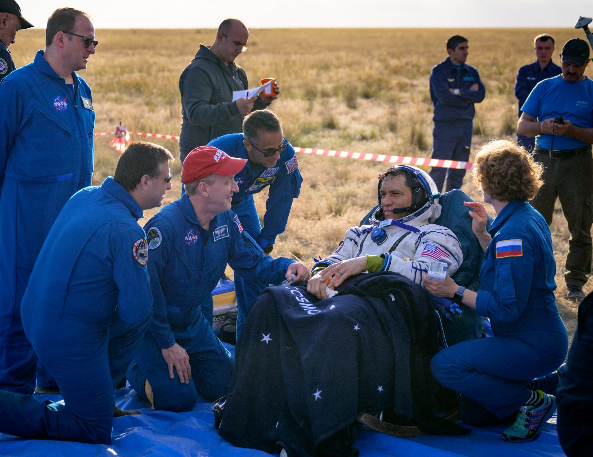 Expedition 69 NASA astronaut Frank Rubio is seen resting and talking with NASA ISS Program Manager Joel Montalbano, kneeling left, NASA Flight Surgeon Josef Schmid, red hat, and NASA Chief of the Astronaut Office Joe Acaba, outside the Soyuz MS-23 spacecraft after he landed with Roscosmos cosmonauts Sergey Prokopyev and Dmitri Petelin in a remote area near the town of Zhezkazgan, Kazakhstan on Wednesday, Sept. 27, 2023.
