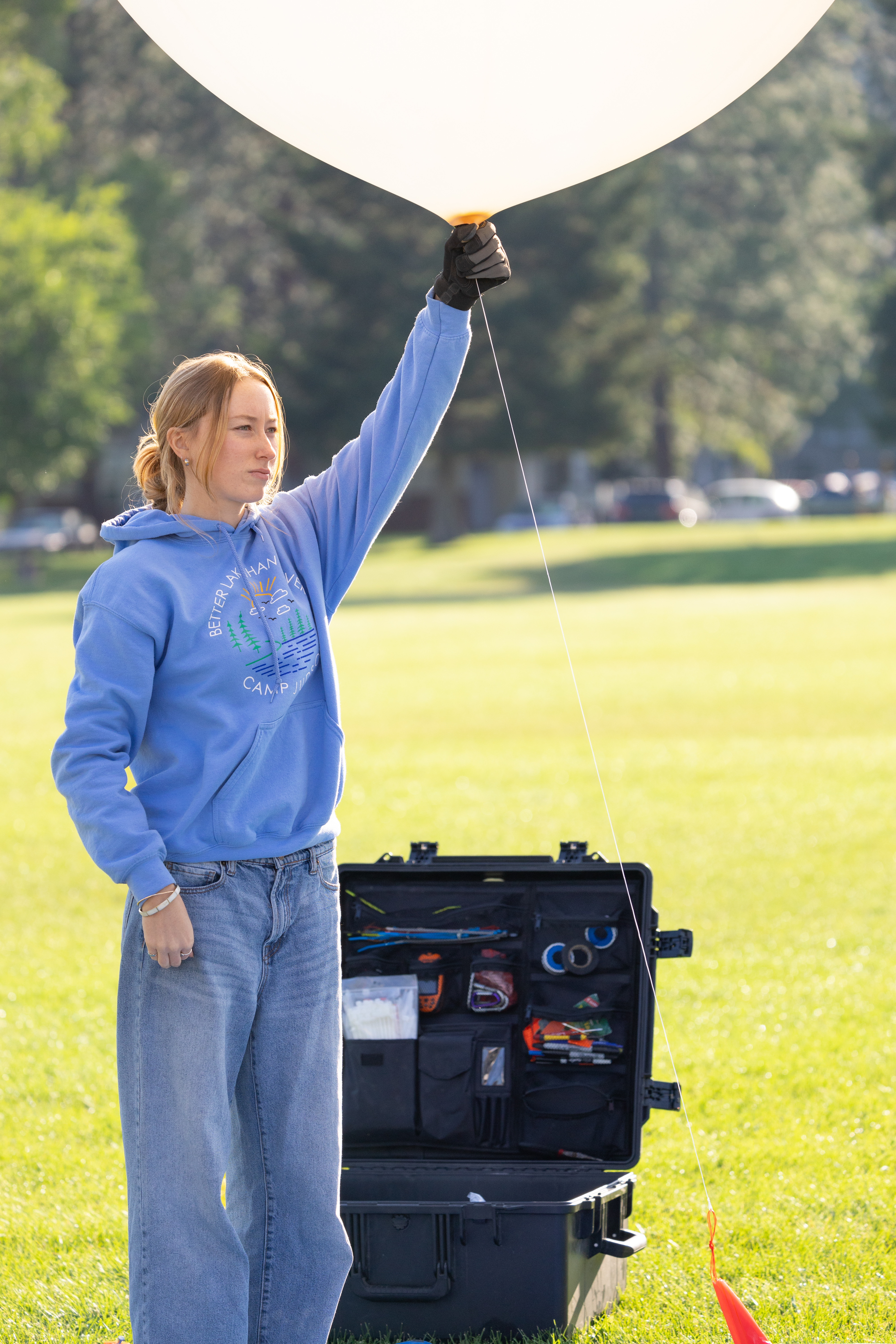 Caeley Hodges, a student at the University of Idaho, holds a weather balloon as the team waits for flight clearance during FireSense’s uncrewed aerial system (UAS) technology demonstration in Missoula, Montana. These balloons use a sensor called a radiosonde to gather data on wind speed and direction.