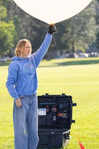 Caeley Hodges, a student at the University of Idaho, holds a weather balloon as the team waits for flight clearance during FireSense’s uncrewed aerial system (UAS) technology demonstration in Missoula, Montana. These balloons use a sensor called a radiosonde to gather data on wind speed and direction.