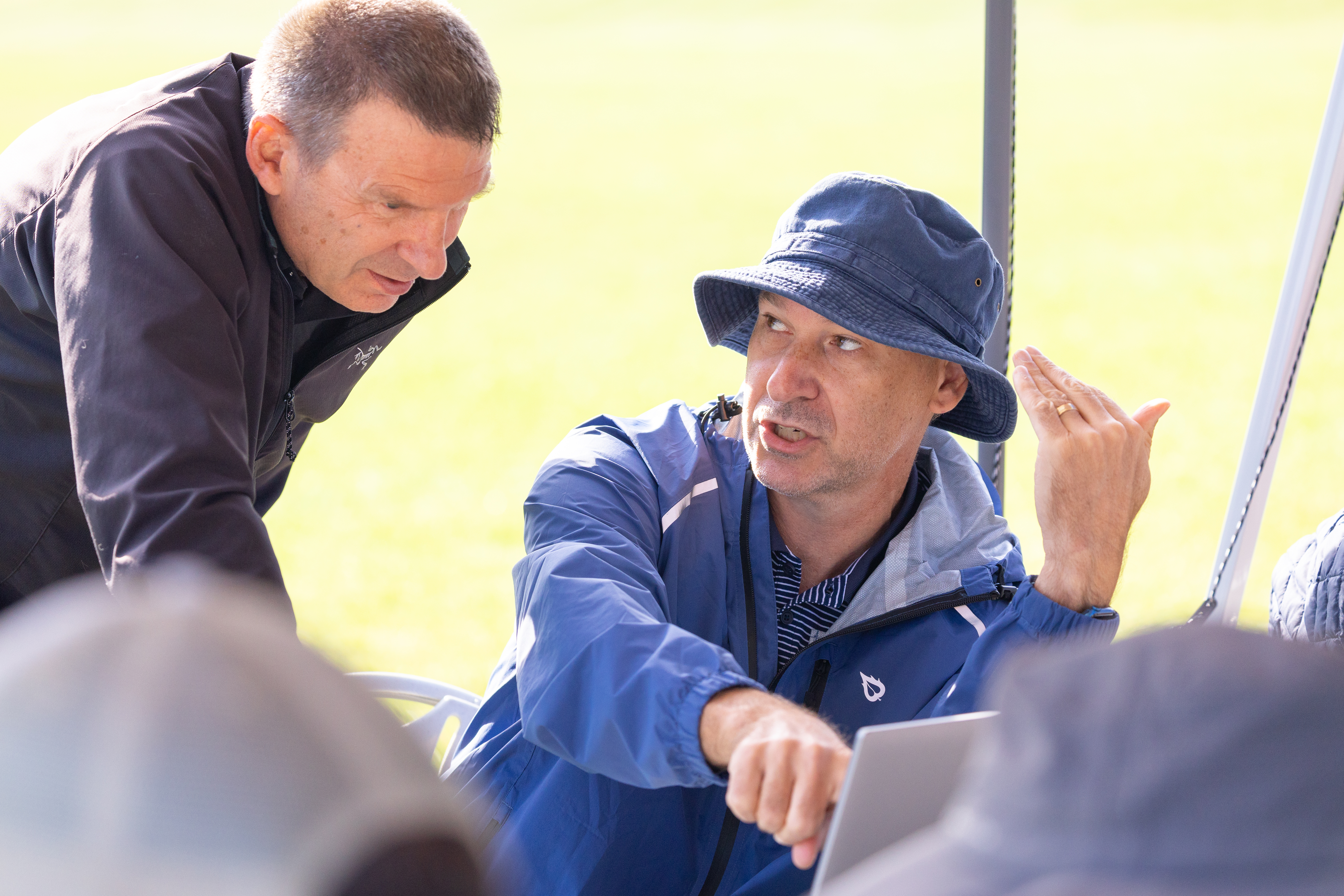 Jim Sharp (Sharp Engineering) looks on as meteorologist Mike Robinson (MITRE), discusses data visualizations of the recent weather balloon launches. The data was collected from a sensor called a radiosonde, attached to weather balloons and launched into the air by several university field teams. Robinson and the MITRE team created visualisations of the flight paths and wind measurements collected across numerous balloon launches throughout the campaign.