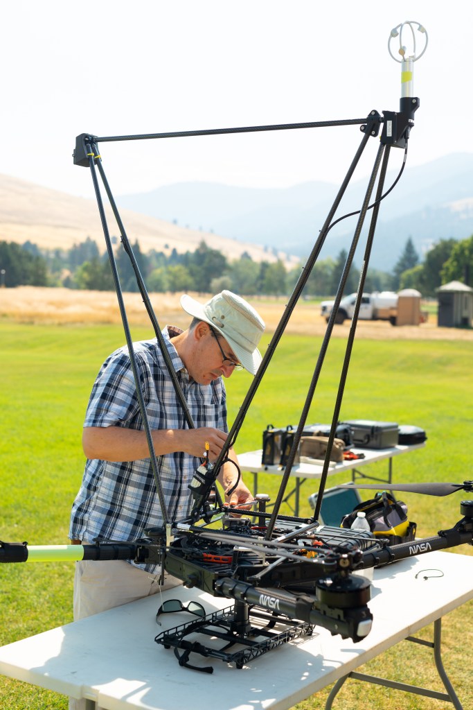 Mechanical engineer Todd Ferrante (NASA Langley) works on the NASA Alta X quadcopter between flights. Mounted on the drone is an infrastructure developed at NASA Langley to fly an anemometer (top right) and radiosonde (not pictured) in order to gather data on wind speed and direction.