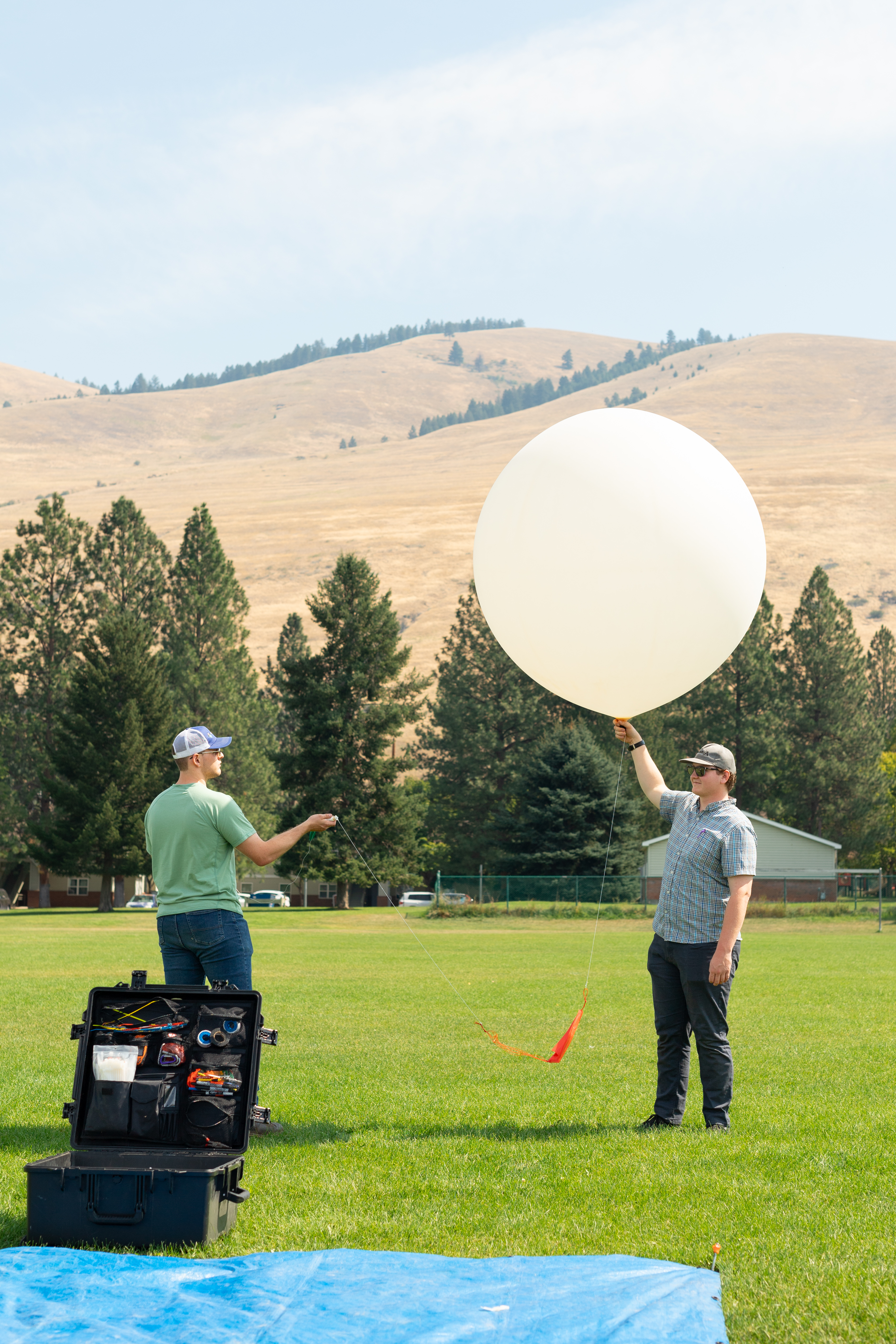 Logan Kearney (left) and Cole Long (right), students at the University of Idaho, release a weather balloon outfitted with a sensor called a radiosonde during the FireSense uncrewed aerial system (UAS) technology demonstration in Missoula, Montana.