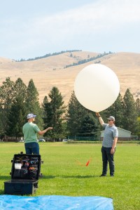 Logan Kearney (left) and Cole Long (right), students at the University of Idaho, release a weather balloon outfitted with a sensor called a radiosonde during the FireSense uncrewed aerial system (UAS) technology demonstration in Missoula, Montana.