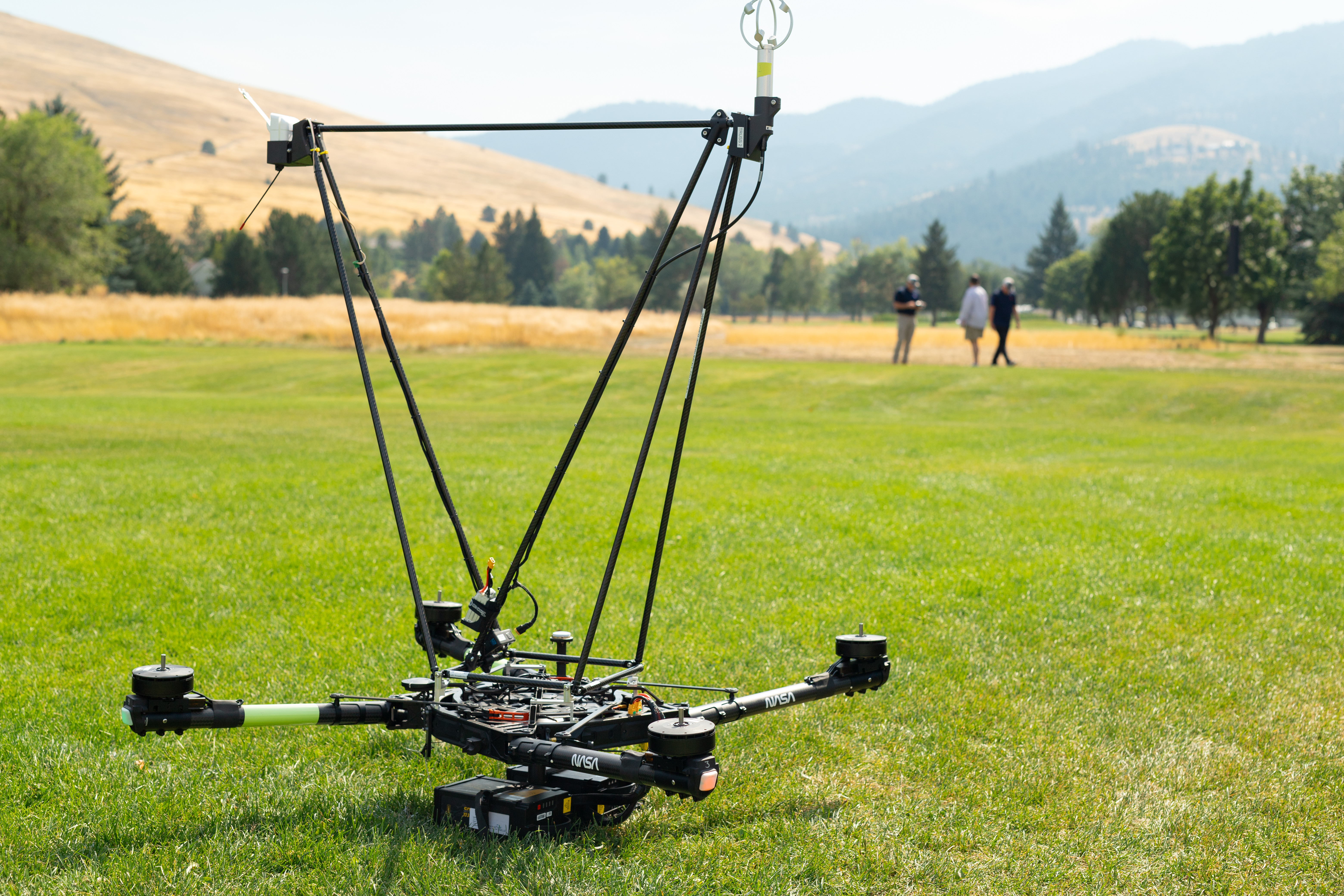 The NASA Alta X quadcopter sits in a field in Missoula, Montana, outfitted with a structure engineered at Langley Research Center to carry a radiosonde (top left) and an anemometer (top right) into the air. The drone and its payload were part of the August 2024 FireSense campaign, which looked at the applicability of using controllable, repeatable airborne measurements to more accurately predict fire and smoke behavior.