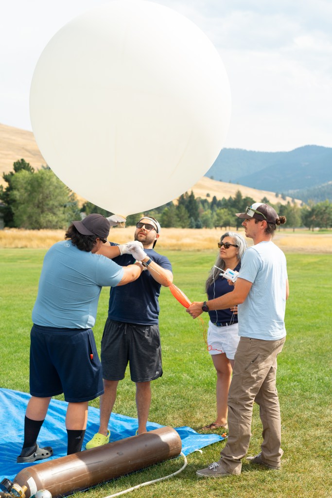 (From left) Travis Christopher, Danny Johnson, Meredith Heckler, and Steven Stratham prepare a weather balloon for launch. This team from Salish Kootenai College is one of two teams that supported the FireSense UAS Technology Demonstration in Missoula, Montana.