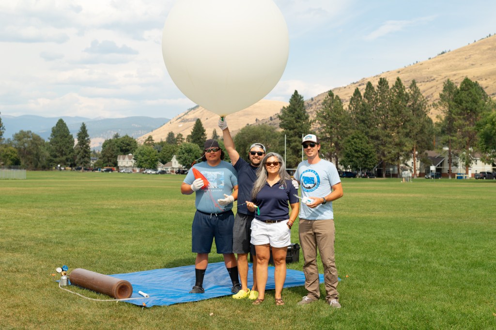 (From left) Travis Christopher, Danny Johnson, Meredith Heckler, and Steven Stratham pose with a weather balloon. This team from Salish Kootenai College is one of two teams that supported the FireSense UAS Technology Demonstration in Missoula, Montana.