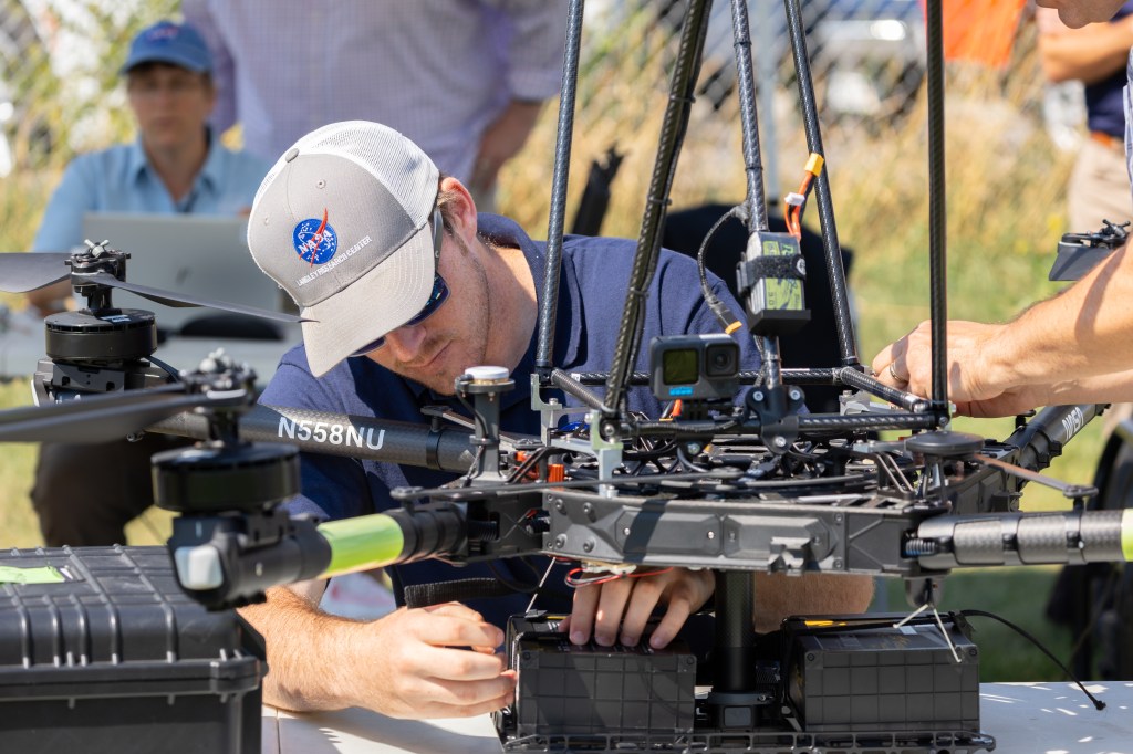 UAS Pilot in Command Brayden Chamberlain works to diagnose a calibration issue with the NASA Alta X quadcopter during the FireSense uncrewed aerial system (UAS) Technology Demonstration in Missoula, Montana.