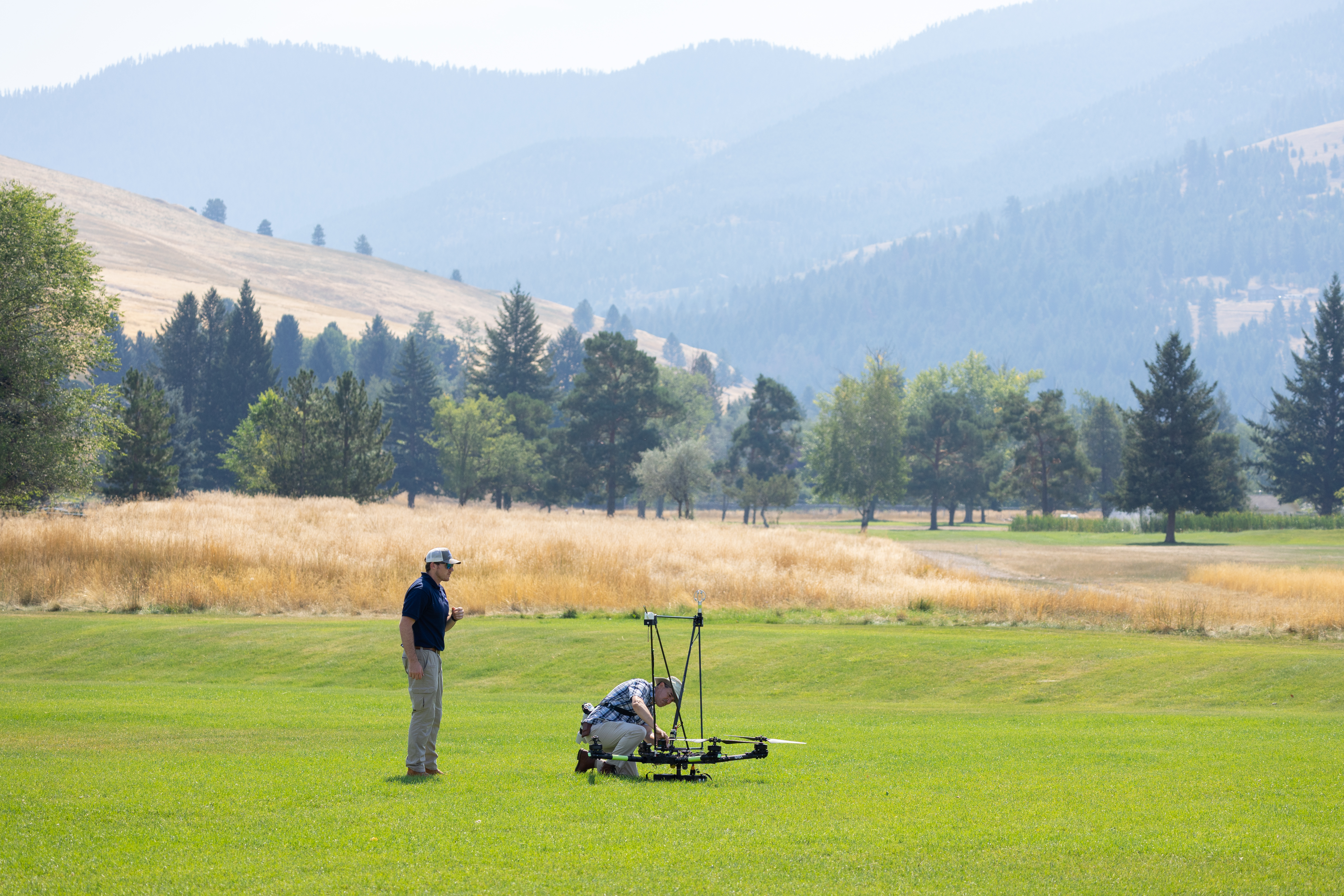 UAS Pilot in Command Brayden Chamberlain (left) and mechanical engineer Todd Ferrante (right) perform final checks on the NASA Alta X quadcopter before a launch, during the FireSense uncrewed aerial system (UAS) technology demonstration in Missoula, Montana.
