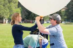 (From left) Caeley Hodges, Logan Kearney, and Cole Long, from the University of Idaho, tie off an weather balloon in preparation for launch during FireSense’s uncrewed aerial system (UAS) technology demonstration in Missoula, Montana. These balloons use a sensor called a radiosonde to gather data on wind speed and direction.