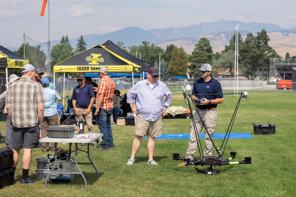 Robert McSwain, FireSense UAS Lead, speaks with UAS Pilot in Command Brayden Chamberlain next to the NASA Alta X quadcopter, between launches for the FireSense’s uncrewed aerial system (UAS) technology demonstration in Missoula, Montana.