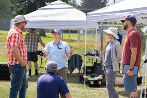 FireSense Project Manager Jennifer Fowler (center, blue hat) and FireSense Project Scientist Jacquelyn Shuman (second from right) speak with visitors from the US Forest Service, Region 1, during the FireSense uncrewed aerial system (UAS) Technology Demonstration in Missoula, Montana.