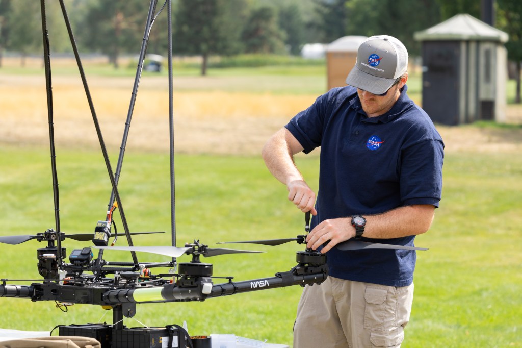 UAS Pilot in Command Brayden Chamberlain tightens a rotor blade on the NASA Alta X quadcopter during the FireSense uncrewed aerial system (UAS) Technology Demonstration in Missoula, Montana.