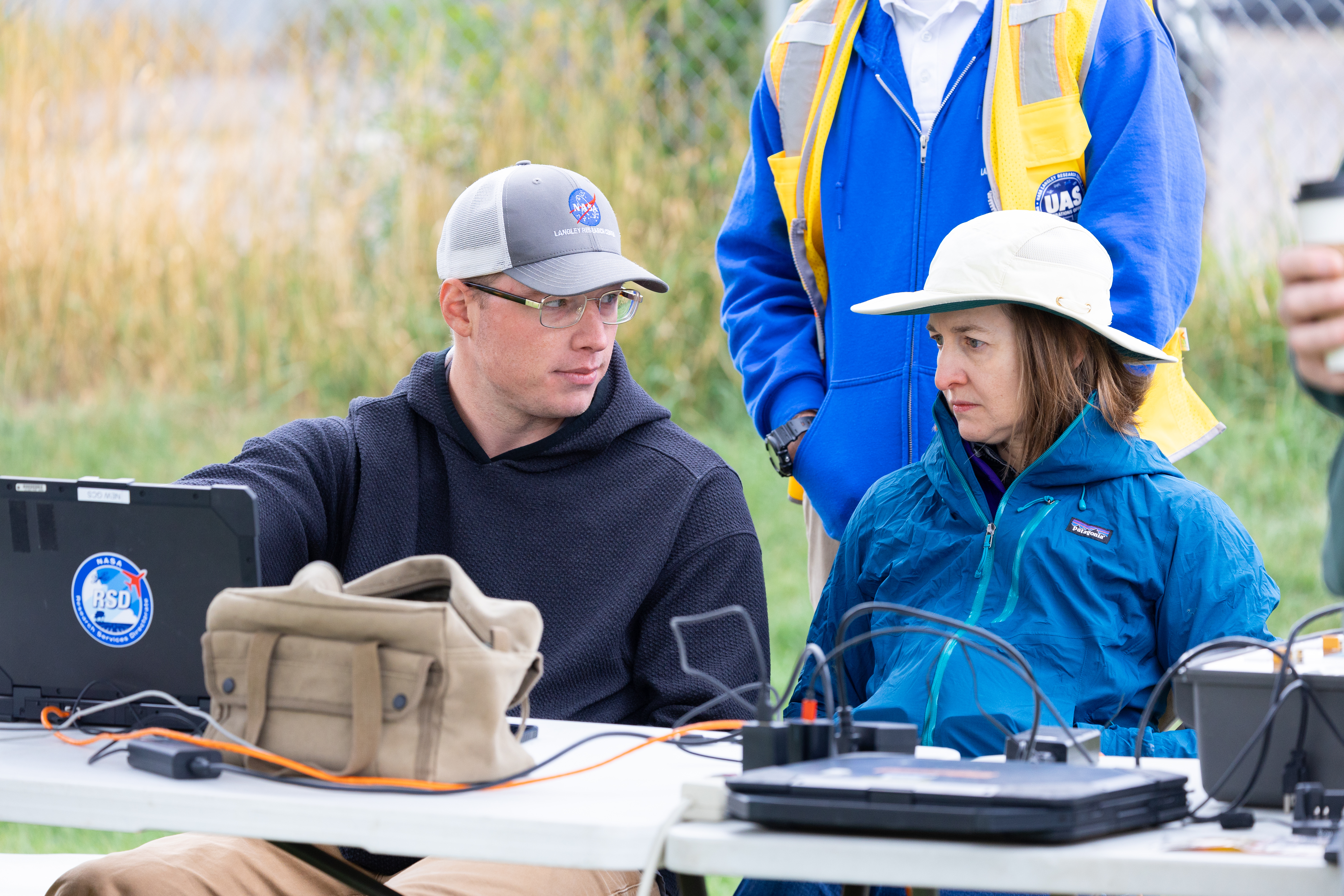 UAS Ground Station Operator Jacob Revesz (left) explains the ground operations of a drone flight to FireSense Project Scientist Jacquelyn Shuman during the FireSense uncrewed aerial system (UAS) Technology Demonstration in Missoula, Montana.