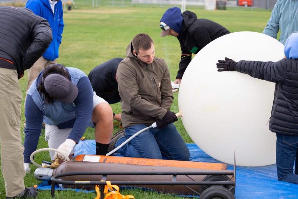 Danny Johnson (left) and Travis Christopher (right) inflate a weather balloon ahead of a launch, outfitted with a radiosonde sensor to gather data on wind speed and direction. This team from Salish Kootenai College is one of two teams that supported the FireSense UAS Technology Demonstration in Missoula, Montana.