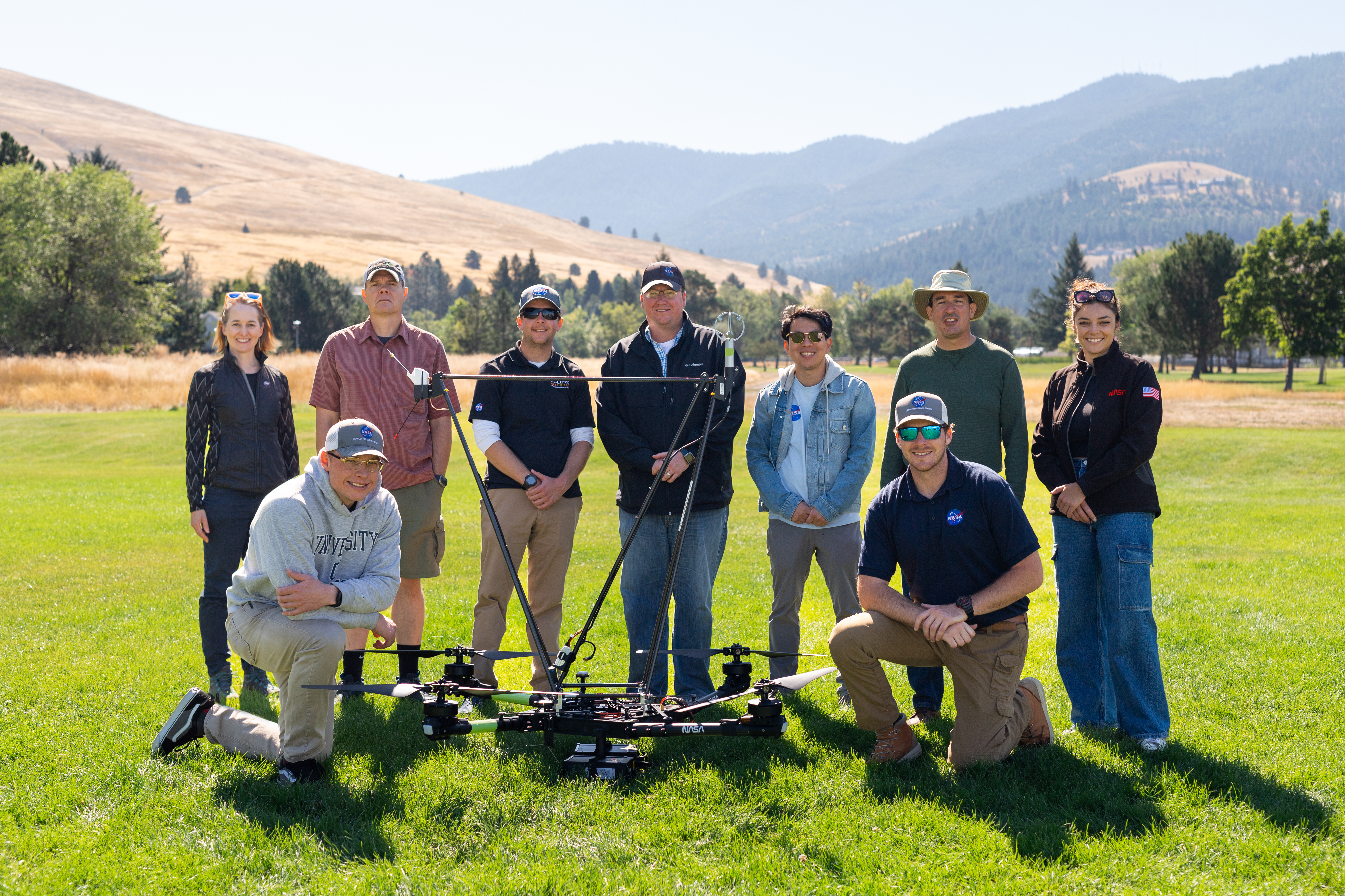The NASA team deployed for the August 2024 FireSense field campaign in Missoula, Montana, stands in a field with the NASA Alta X quadcopter. The campaign involved members of the FireSense Project Office, the NASA Langley drone team, logistics support from the Earth Science Project Office, and communications from NASA Ames Earth Science Division. (Not pictured: NASA FireSense Project Manager Jennifer Fowler, also present for the campaign).