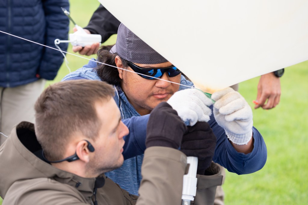 Danny Johnson (back) and Travis Christopher (front) tie off a weather balloon ahead of a launch, outfitted with a radiosonde sensor to gather data on wind speed and direction. This team from Salish Kootenai College is one of two teams that supported the FireSense UAS Technology Demonstration in Missoula, Montana.