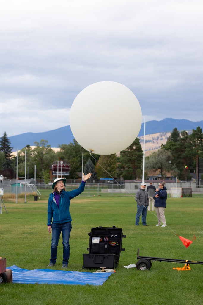 FireSense Project Scientist Jacquelyn Shuman releases a weather balloon into the sky on the last day of the FireSense uncrewed aerial system (UAS) Technology Demonstration in Missoula, Montana. The weather balloon is outfitted with a radiosonde sensor, which provides data on wind speed and direction.