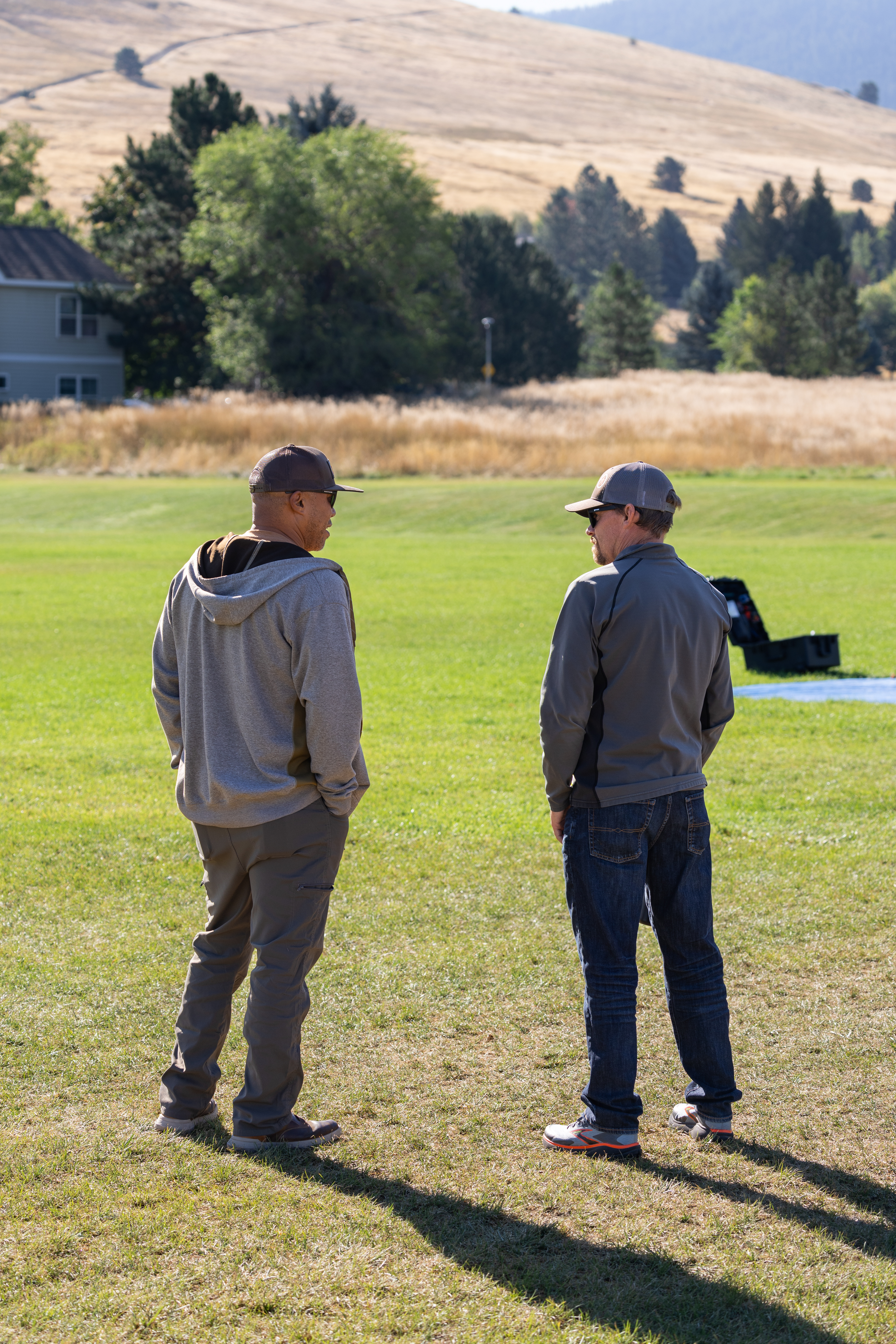 US Forest Service members Chris Bolz (left) and Evan Day (right) watch the final launch of the NASA Alta X quadcopter during the FireSense uncrewed aerial system (UAS) technology demonstration in Missoula, Montana. The US Forest Service is a potential user of this technology, as increased accuracy and repeatability of wind forecasting could greatly improve fire behavior predictions.