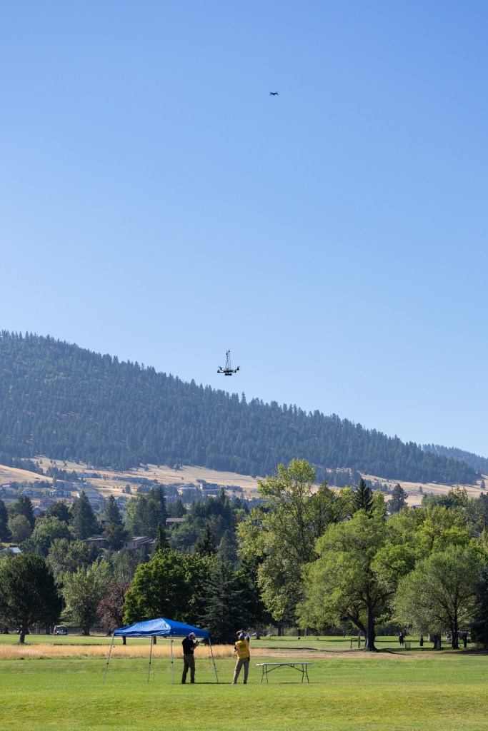 UAS Pilot in Command Brayden Chamberlain (left) and Range Safety Officer Dustin Schmitt (right) watch the NASA Alta X quadcopter as it descends from its final flight of the FireSense uncrewed aerial system (UAS) technology demonstration in Missoula, Montana.