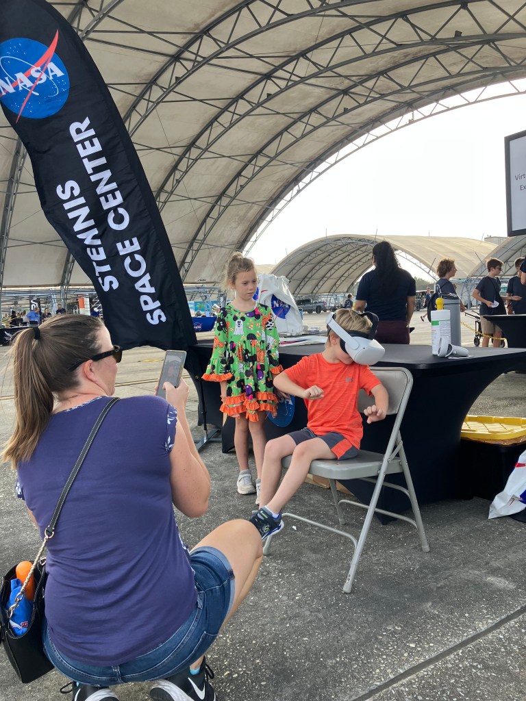 A young attendee at the NAS Pensacola Blue Angels Homecoming Air Show using virtual reality device provided by NASA Stennis representatives