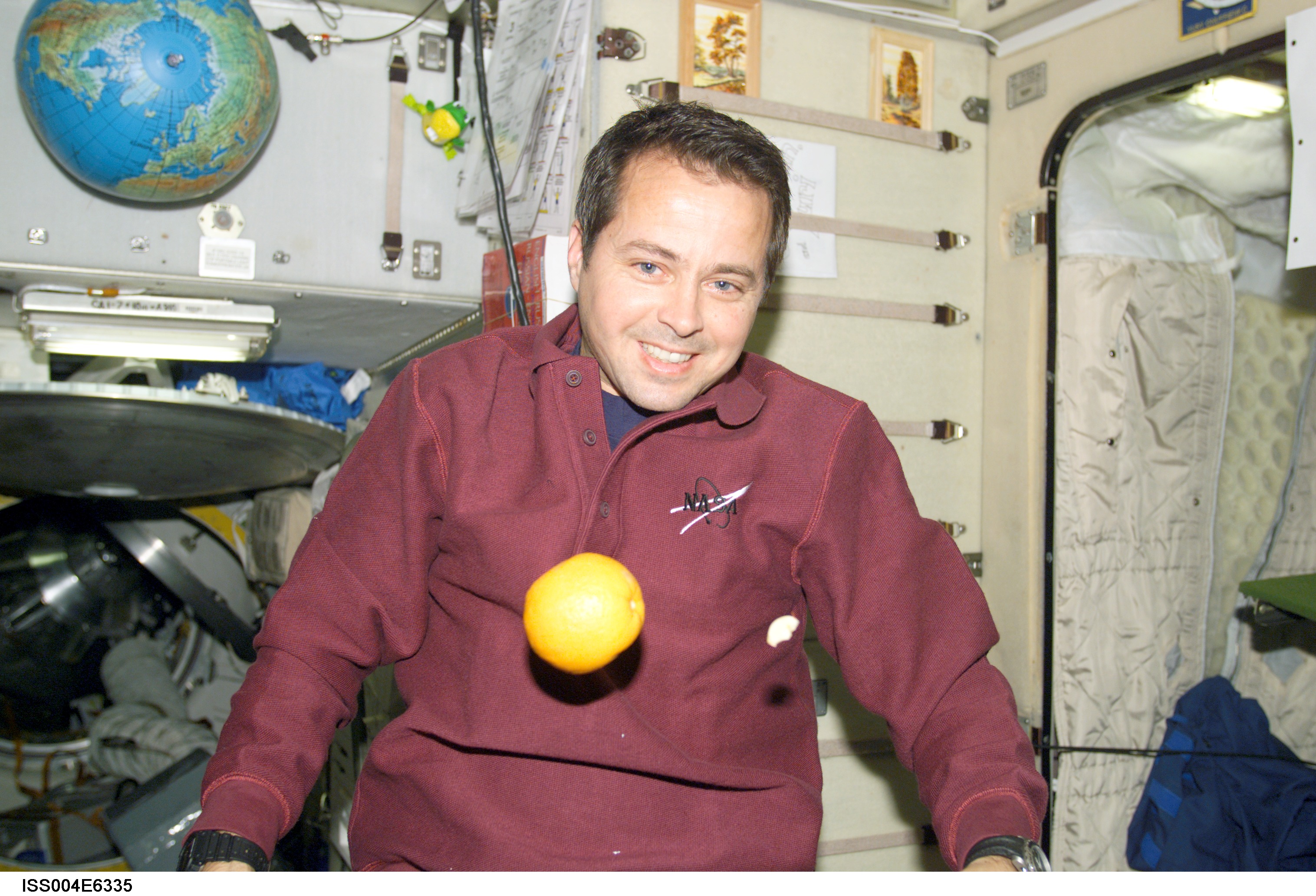 ISS004-E-6335 (January 2002) --- Astronaut Daniel W. Bursch, Expedition Four flight engineer, is photographed in the Zvezda Service Module on the International Space Station (ISS). An orange floats freely in front of Bursch. The image was taken with a digital still camera.