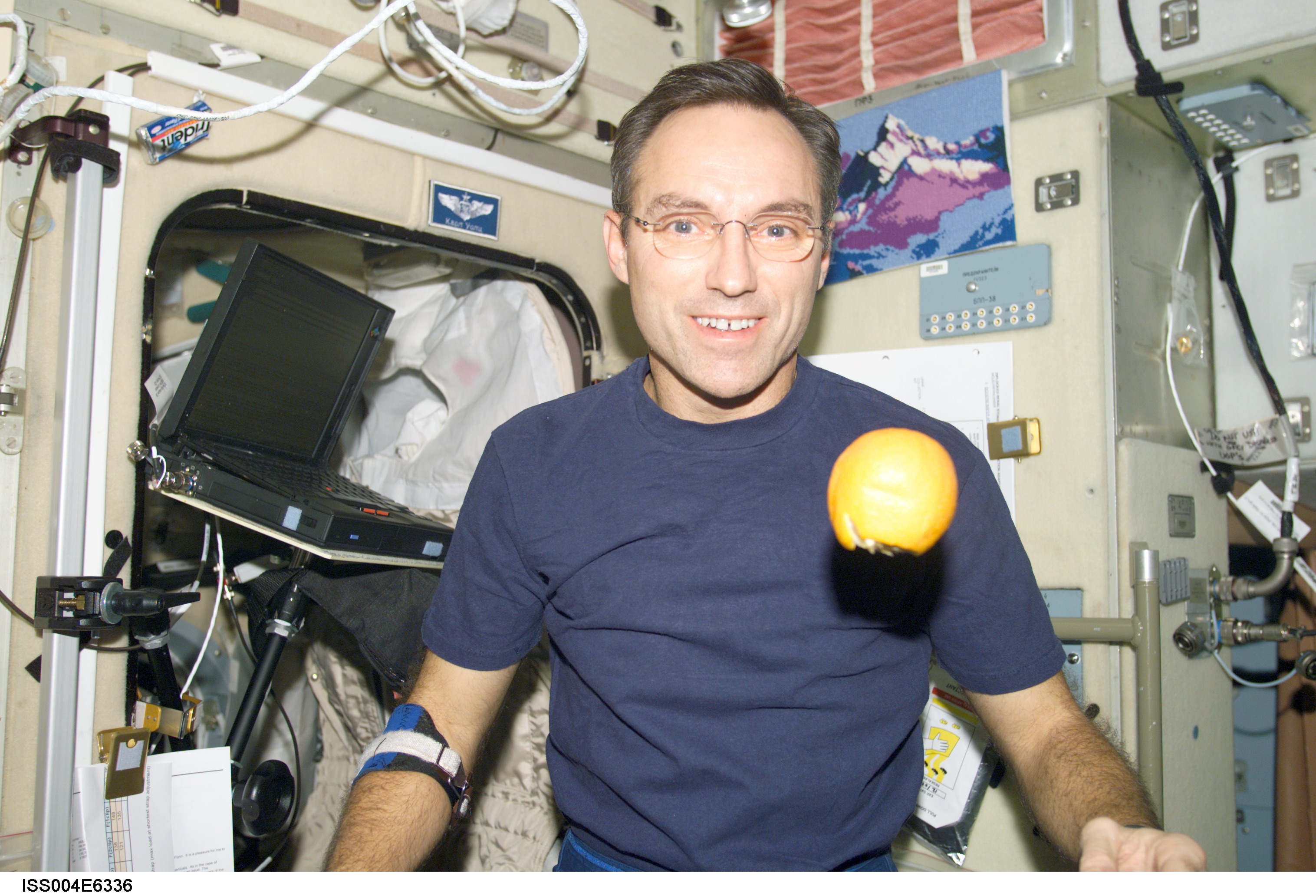 ISS004-E-6336 (January 2002) --- Astronaut Carl E. Walz, Expedition Four flight engineer, is photographed in the Zvezda Service Module on the International Space Station (ISS). An orange floats freely in front of Walz. The image was taken with a digital still camera.
