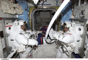 ISS004-E-8037 (20 February 2002) --- Astronauts Carl E. Walz (left) and Daniel W. Bursch, Expedition Four flight engineers, undergo a pressure check in Quest's Equipment Lock, prior to the beginning of what turned out to be a five-hour, 47-minute session of extravehicular activity (EVA). The image was recorded with a digital still camera.